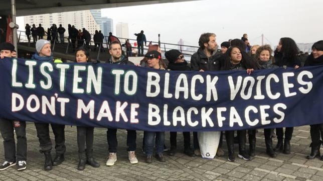 Demonstranten gijzelen om de koloniale blackface-figuur te beschermen